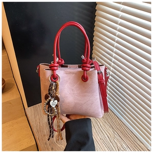 Detail of pink and red contrast handbag featuring a heart tag and fringe tassel charm