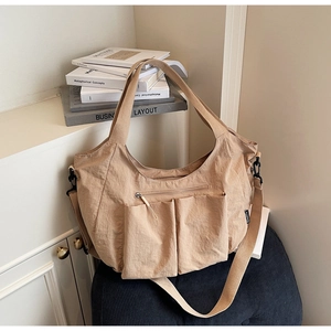Detail of khaki tote bag with pleated texture and functional multi-pocket design features