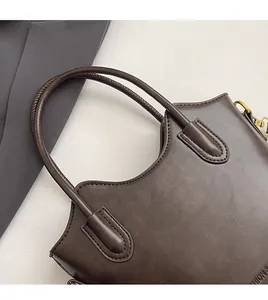 Detail of reinforced handles and texture on this dark brown synthetic leather bucket bag