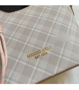 Dettaglio della borsa a quadri beige con logo dorato e trama in pelle a grana fine