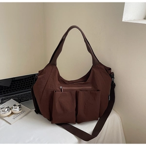 Detailed view of brown nylon tote bag featuring multiple pockets and adjustable shoulder strap