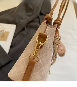 Dettaglio della borsa beige trapuntata con finiture dorate e nappa intrecciata