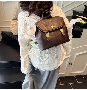 Detail of vintage dark brown leather backpack with gold metal twist lock and handle