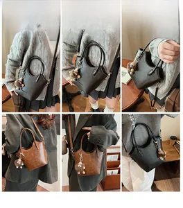 Detail shot of stylish bucket bag with cute plush pendant shown in black and brown colors