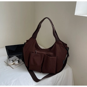 Detail of coffee tote bag with front pockets, laptop, and headphones on white background