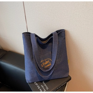 Detail of blue denim tote bag featuring yellow Today Mood embroidery and side label