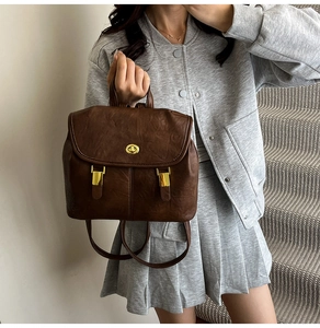 Detail of dark brown leather backpack with golden oval twist lock and pebbled texture