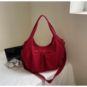 Detail of red large capacity nylon tote bag showing multiple functional front pockets