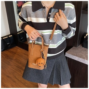 Brown bucket crossbody bag detail featuring a cute puppy charm and checkered silk scarf