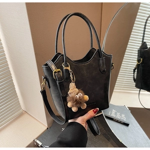 Detail of black matte bucket bag with golden hardware and plush doll pendant