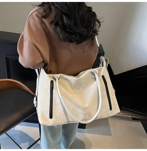 Detail of a large off-white travel tote bag with black zippers and a round embossed logo