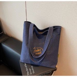 Close-up of deep blue denim tote bag with orange Today Mood embroidery detail