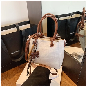 Detail of vintage beige bucket bag showing textured finish and brown bow charm
