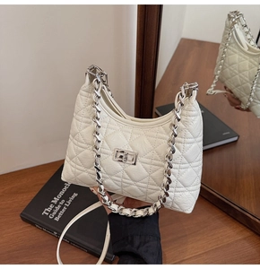 Macro shot of white quilted leather bag with silver twist lock and chain strap details