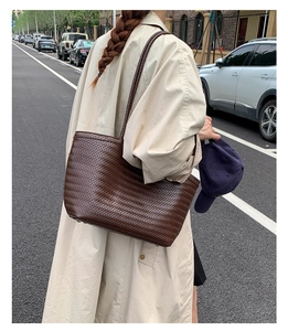 Détail d'un cabas en cuir tressé marron foncé porté par un mannequin dans un style urbain