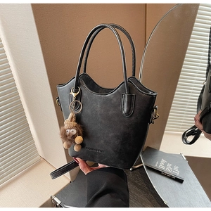 Detail of black wave-top bucket bag with plush charm and Fashion & Bags gold lettering
