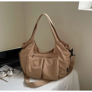 Detailed macro view of khaki nylon tote bag featuring two large functional front pockets