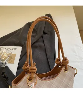 Dettaglio del manico arrotondato con nodo e anello dorato su questa borsa a secchiello