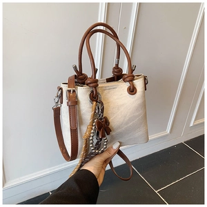 Detail of vintage beige bucket bag featuring brown handles and sphere knot accents
