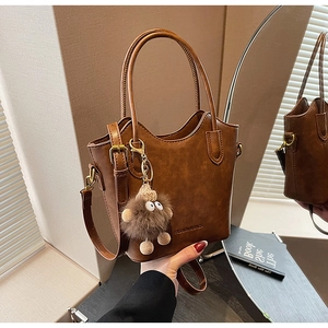Detail of dark brown leather bucket bag with plush charm and FASHION & BAGS logo print