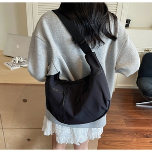 Photo lifestyle d'un grand sac croissant en nylon noir avec large bandoulière