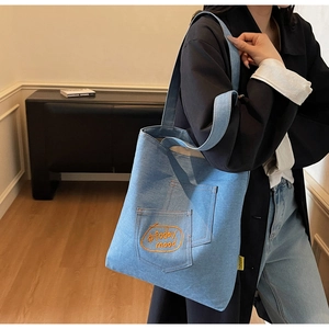 Detail of light blue denim tote bag with orange #today mood embroidery and yellow side tag