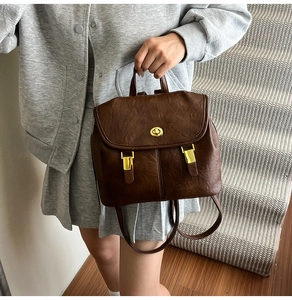 Detail of vintage brown leather backpack featuring a gold clasp held by a model