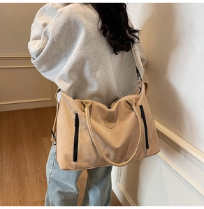Detail view of large beige tote bag with twin vertical zippers and adjustable strap