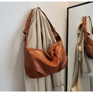 Detail of caramel hobo bag featuring soft pleated leather and stylish knotted shoulder strap