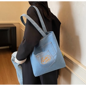 Close-up of light blue denim tote bag with orange #today mood pocket embroidery