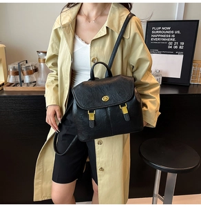 Detail of black lychee grain leather backpack with gold rotating lock and vintage flap