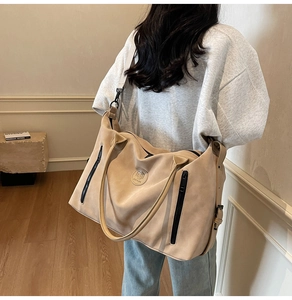 Detail of large beige travel bag featuring vertical zippers and a stylish round logo