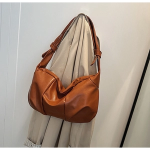 Detail of a brown slouchy hobo bag featuring a knotted strap and pleated faux leather