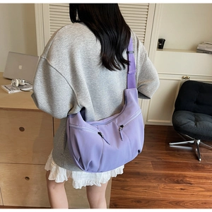 Détail du sac bandoulière en nylon violet avec plusieurs poches zippées et bandoulière