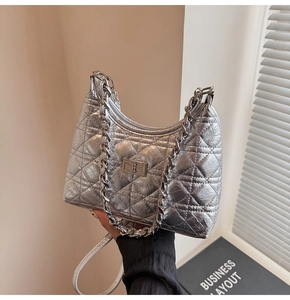 Close-up of silver quilted shoulder bag with metal chain strap and turn-lock closure