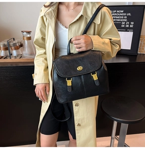 Detail of a vintage black leather backpack with gold rotating lock and matte texture