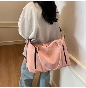 Pink matte duffel bag with black straps worn by model in a minimalist home setting