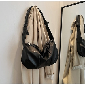 Detail of black faux leather dumpling bag with silver round zipper and wide strap