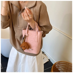 Détail d'un sac seau en similicuir rose avec breloque ours et plaque métallique