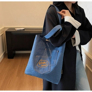 Detail of blue denim tote bag featuring orange #today mood embroidery on front pocket