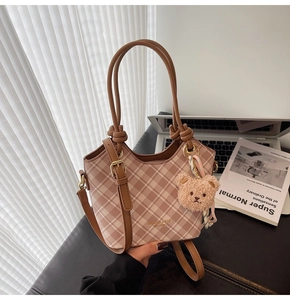 Dettaglio della borsa tote a quadri rosa con cinturini in pelle e ciondolo a orsetto