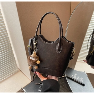 Detail of dark brown leather bucket bag with plush charm and fashion embossing