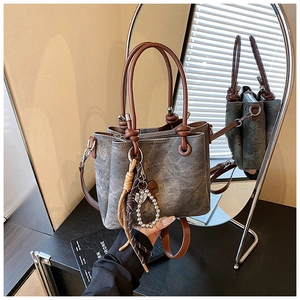 Detail of vintage retro bucket bag with decorative charm and textured material surface