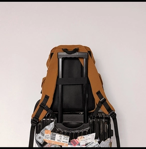 Detalle de mochila de viaje color caramelo con cinta de sujeción para mango de maleta