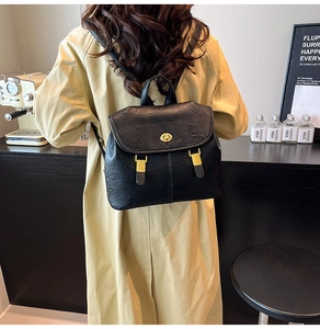 Detail of black PU leather backpack showing golden turn-lock closure and metal hardware