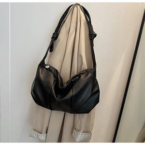 Detail of black soft leather crossbody bag with knot shoulder strap on beige coat