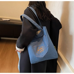 Detail of blue denim tote bag with #today mood embroidery and functional front pocket