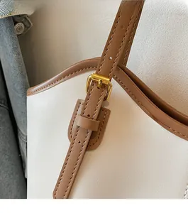 Detail of golden metal buckle and brown leather stitching on minimalist tote bag