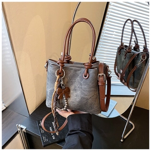 Detail of vintage gray canvas bucket bag with brown leather handles and pearl bow charms