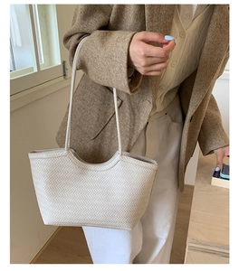 Gros plan sur la texture du sac cabas tissé crème avec des motifs élégants et anses